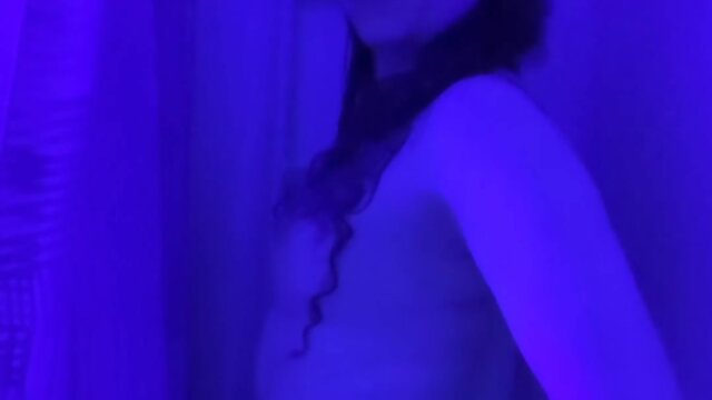 Trans person in bikini strips, showers, and plays under black light